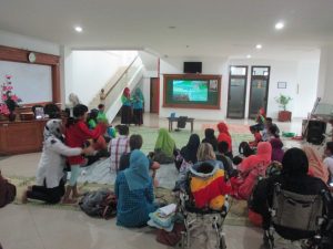 beberapa orang duduk bersama di lantai menonoton video