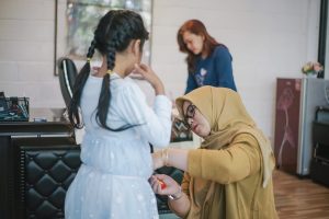 seorang anak perempuan penyandang cerebral palsy sedang diukur badannya oleh seorang fashion desainer